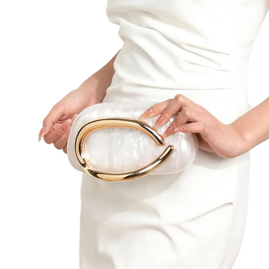 White clutch with gold accents held by a person wearing a white dress.