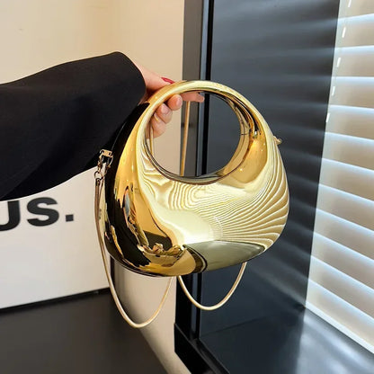 Gold handbag held by a person against a blurred indoor background