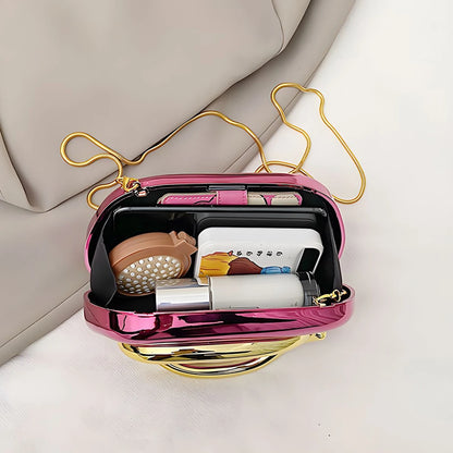 Pink handbag with gold strap containing beauty products on a light background