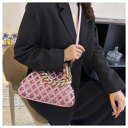 Person holding a pink handbag with gold chain detail, wearing a black suit.