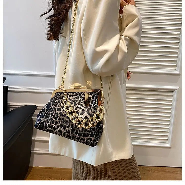 Person wearing a white outfit with a Carauana_UNIU_Leopard_Clutch featuring gold chain details.