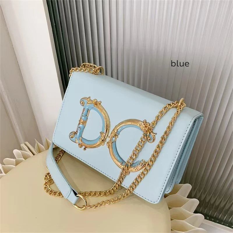Light blue Dolce_CaRaUaNa handbag with gold chain and 'Dior' logo on a white surface.