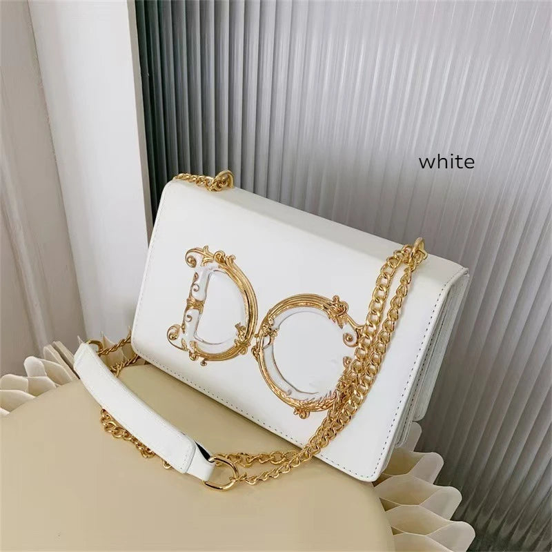 White Dolce_CaRaUaNa handbag with gold chain and decorative logo on a white surface.