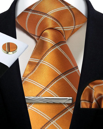 Orange plaid tie set with matching pocket square, cufflinks, and tie clip on a black suit jacket.