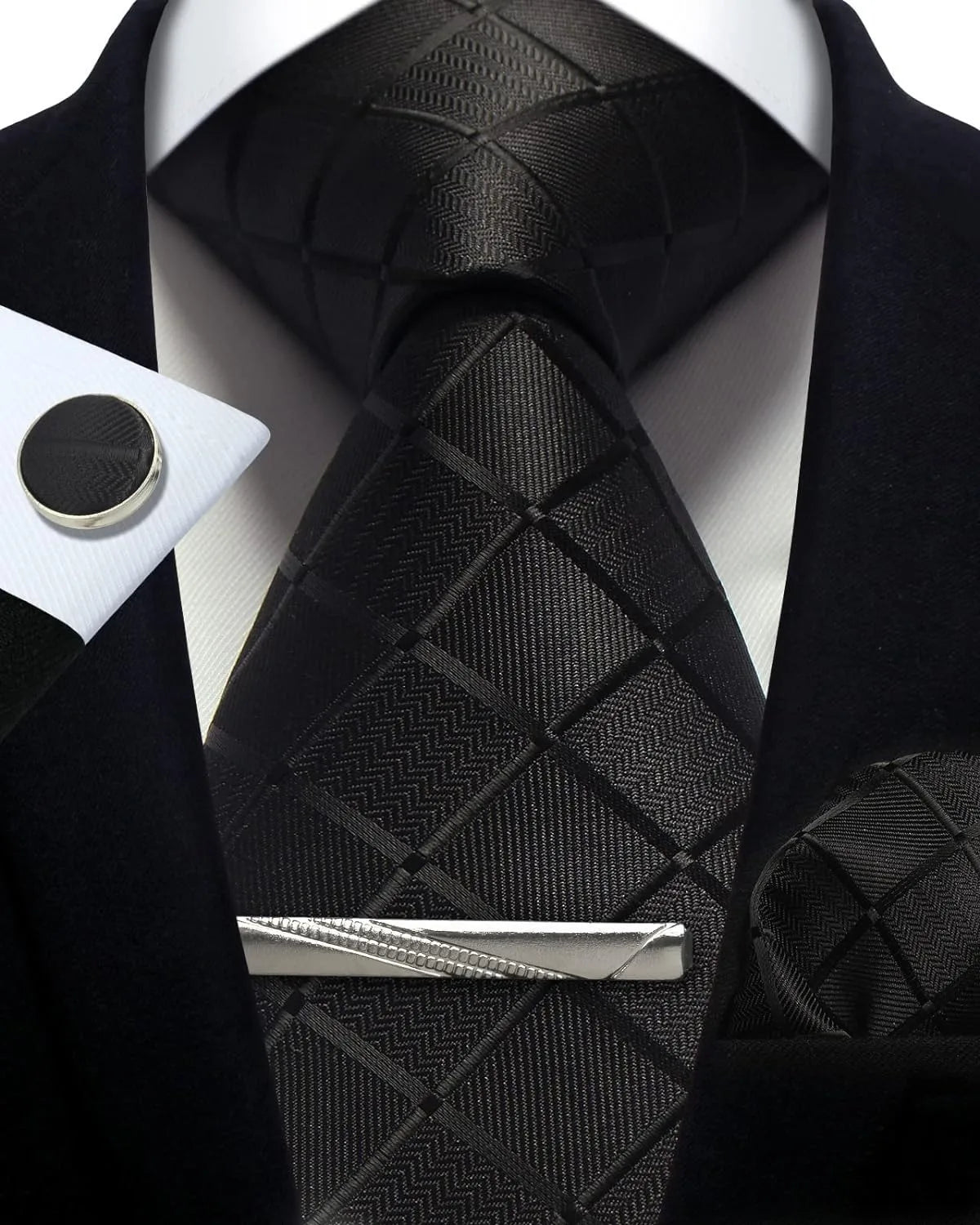 Black patterned tie with matching pocket square and cufflinks on a white shirt.